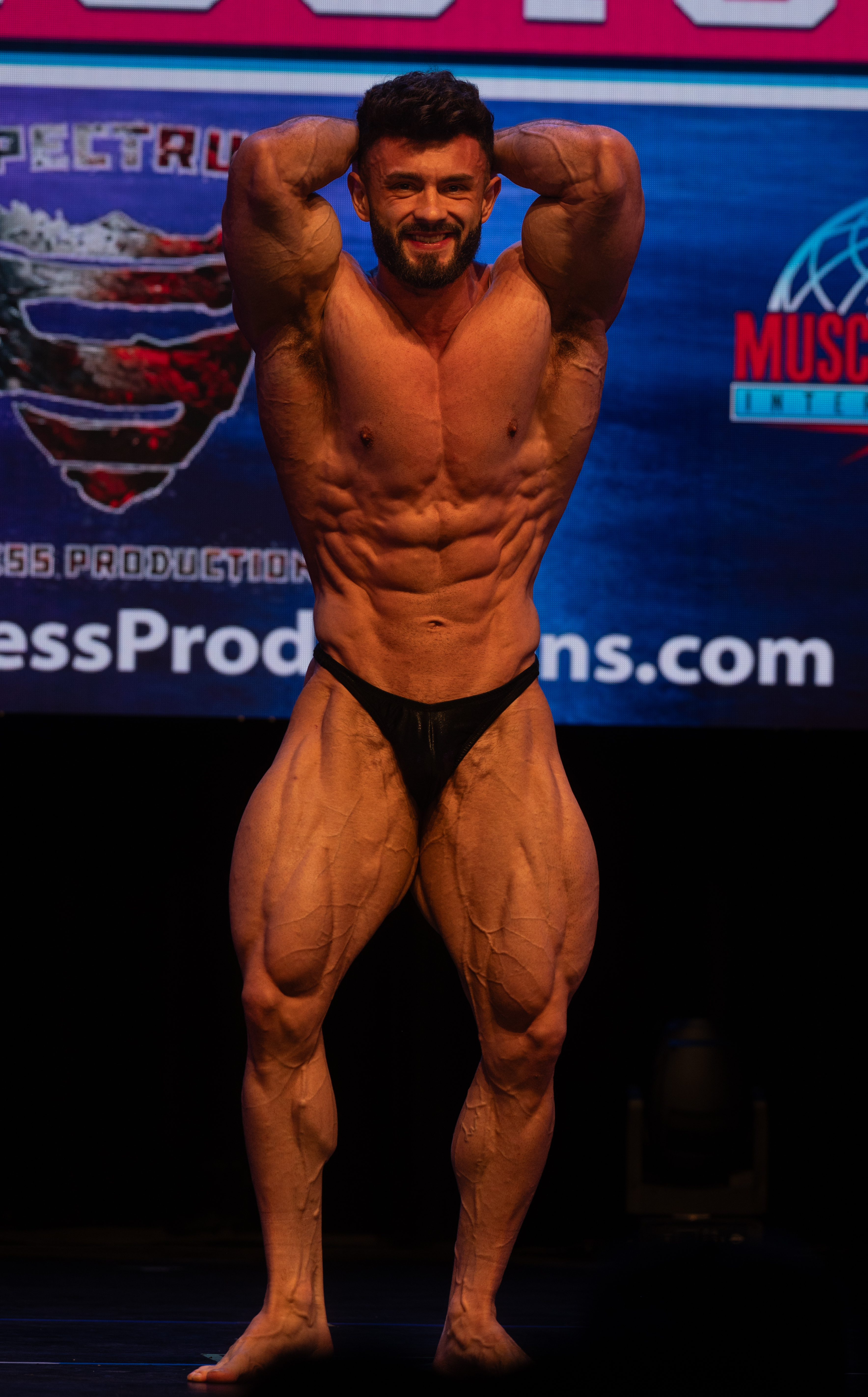 Bodybuilder front double bicep pose on stage